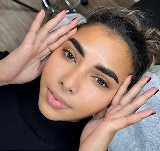 a person getting their eyebrows tattooed at salon.